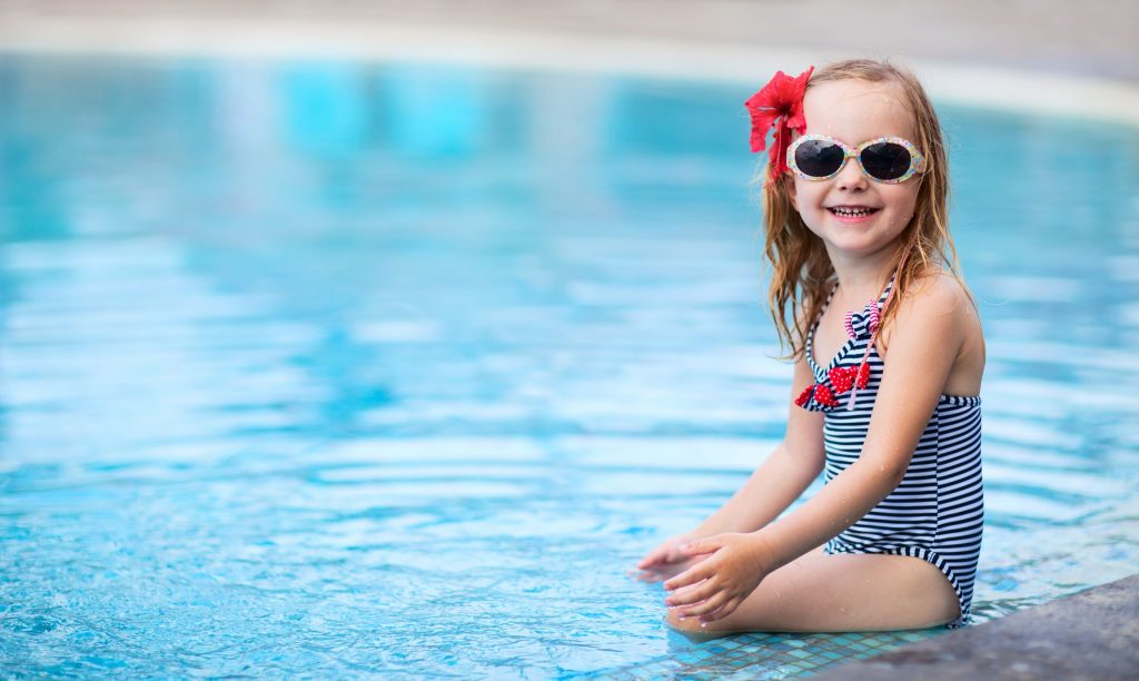 a cute little girl with sunglasses at the pool