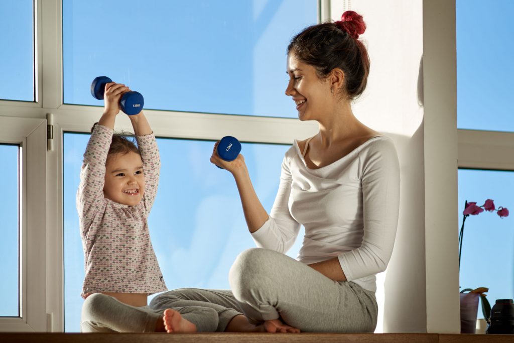 mom and her young daughter lifting dumbbells 