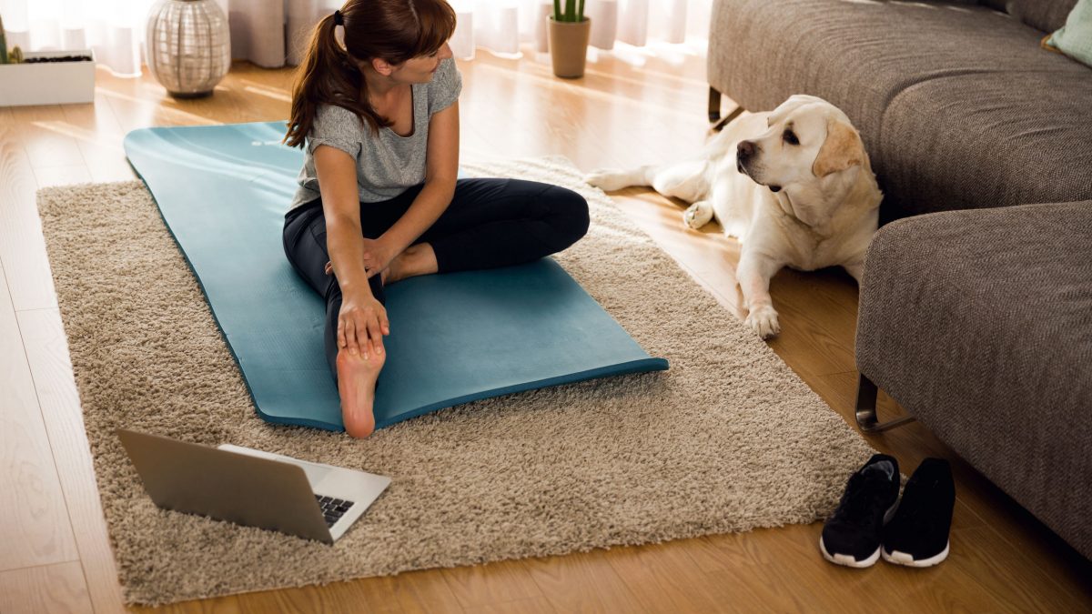 a woman stretching in her living room next to her dog