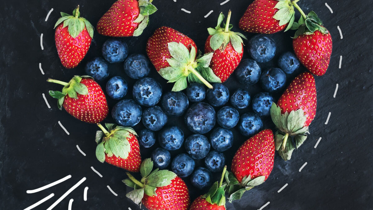 strawberries surrounding blueberries in a heart-shaped outline, symbolizing a healthy Valentine’s Day