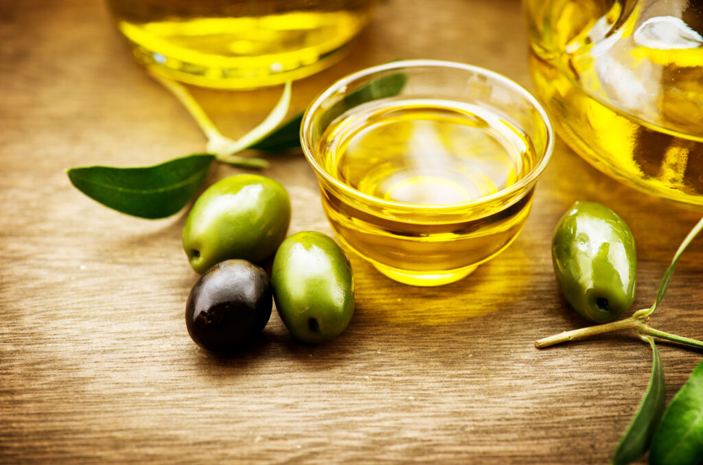 olives on a table next to a small bowl of extra-virgin olive oil