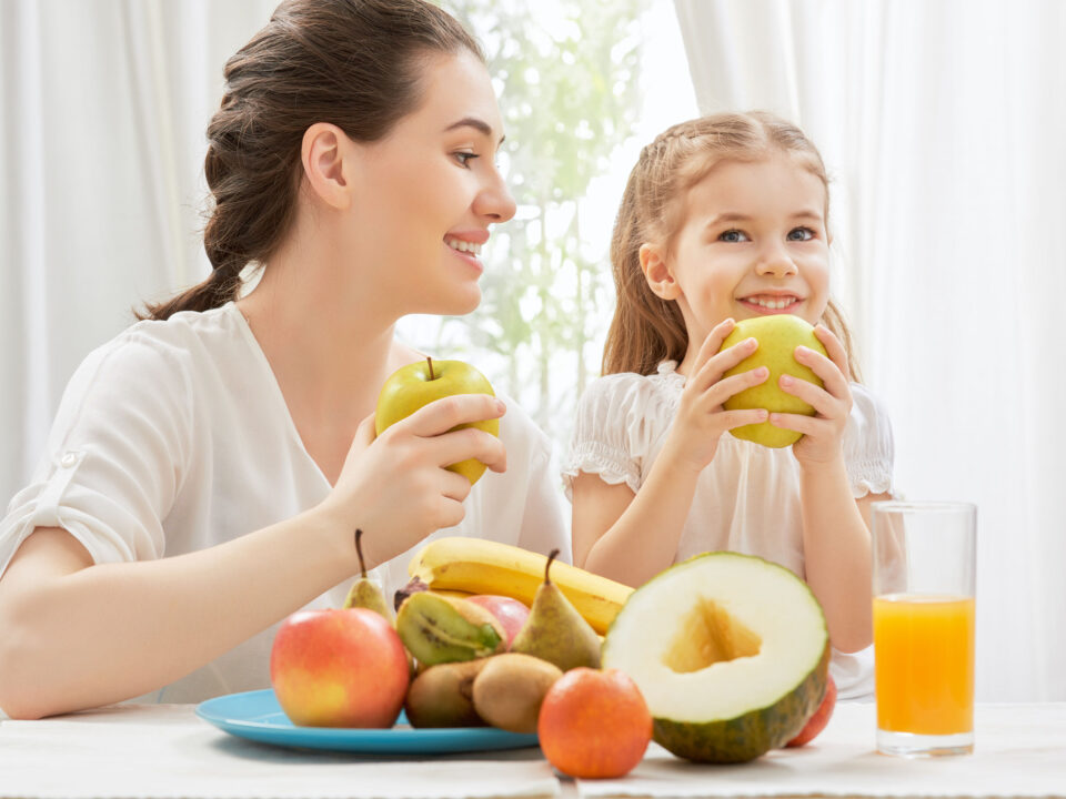 a mom and her daughter eating fresh fruit