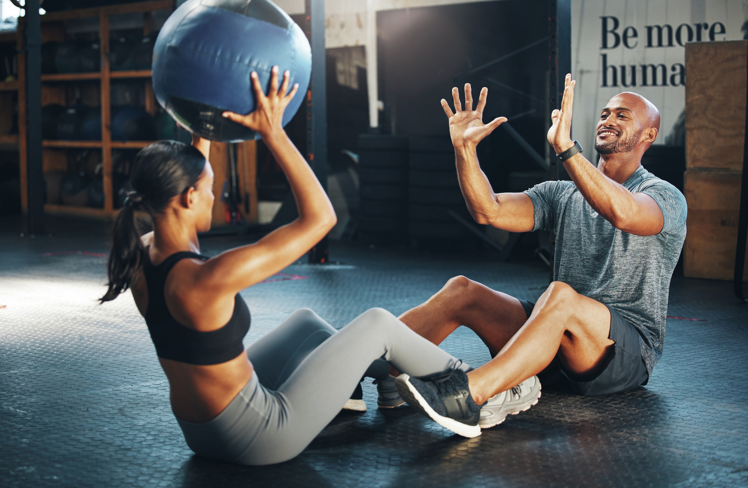Man and woman passing a medicine ball back and forth during partner workouts.