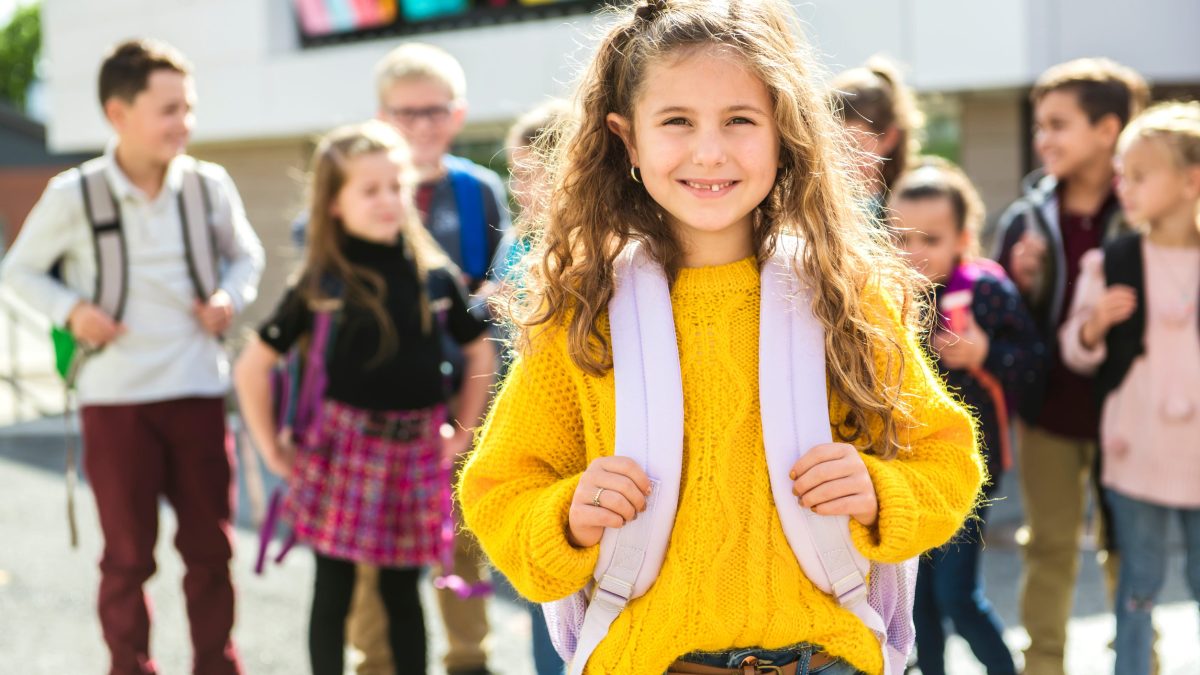 Girl wearing a backpack with her classmates